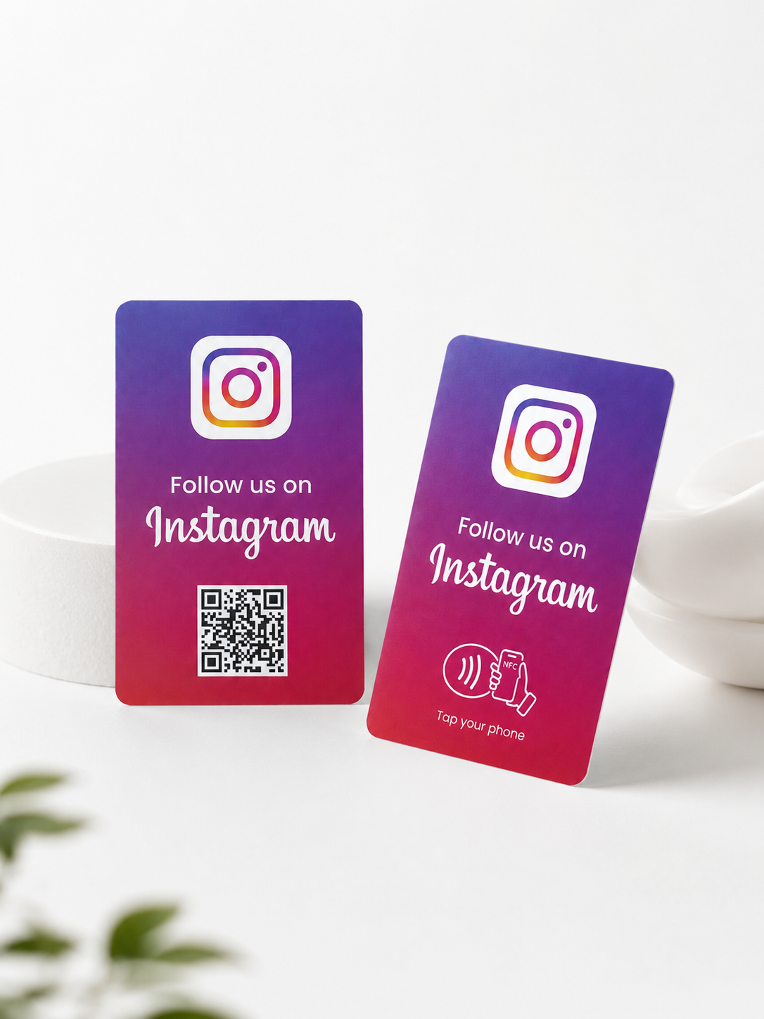Due card NFC Instagram in studio su fondo bianco, una con QR code e una con simbolo NFC